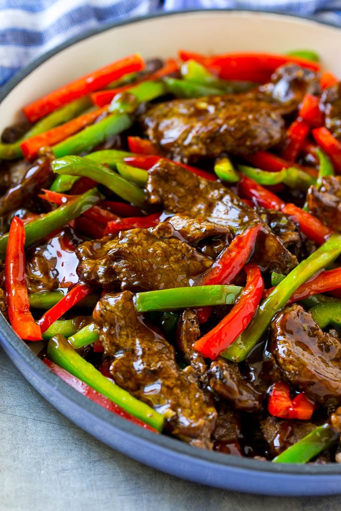 A skillet of Chinese pepper steak coated in a brown soy based sauce.