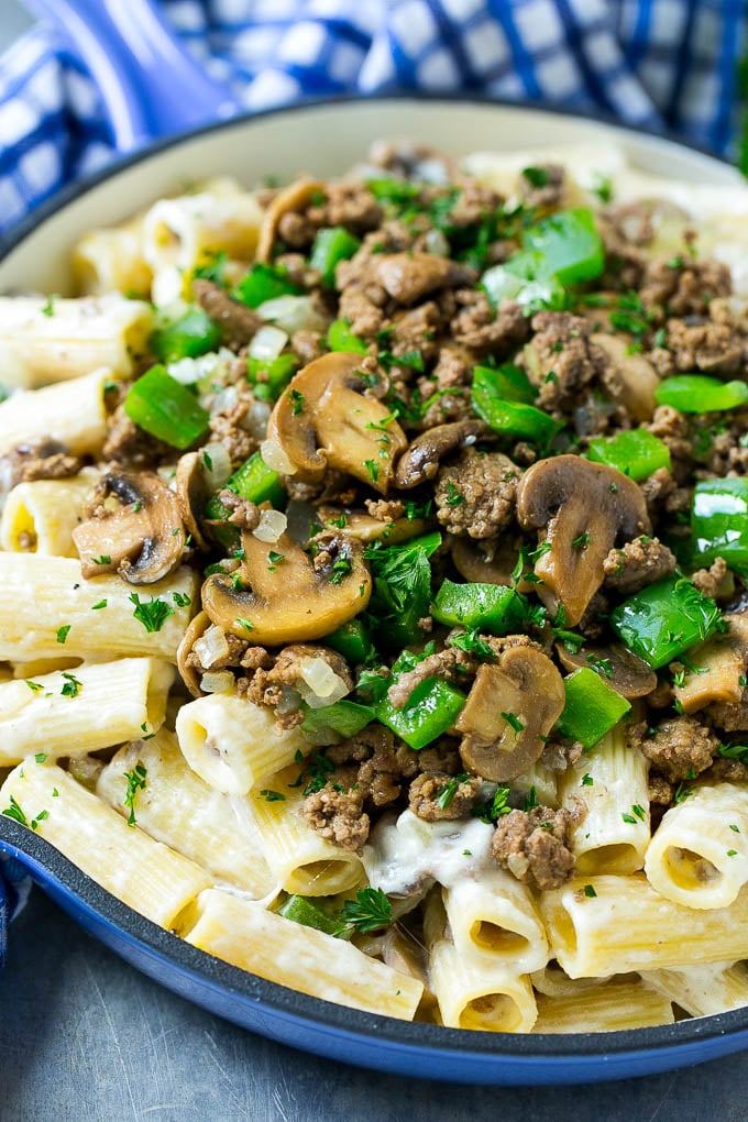 A skillet of philly cheesesteak pasta with creamy rigatoni, ground beef, sauteed mushrooms and green peppers.