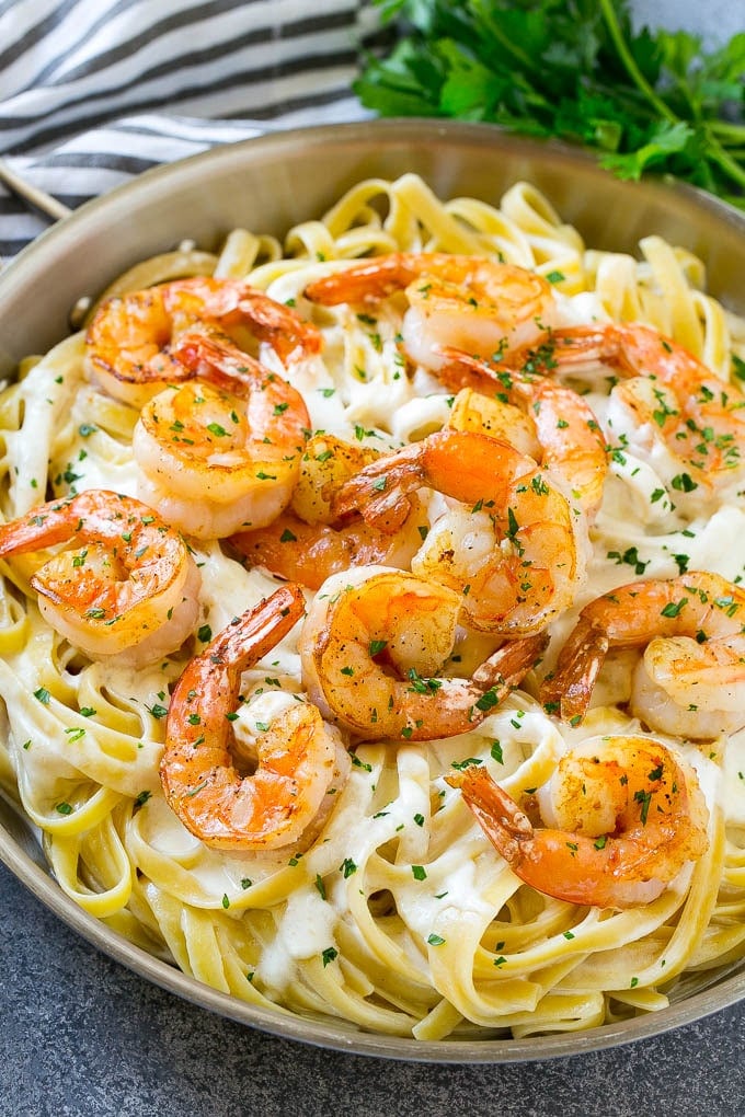 A pan of shrimp alfredo with fettuccine, creamy parmesan sauce and garlic butter shrimp.