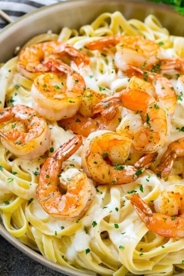 Shrimp alfredo in a skillet, topped with chopped parsley.