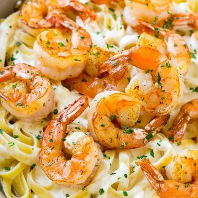 Shrimp alfredo in a skillet, topped with chopped parsley.