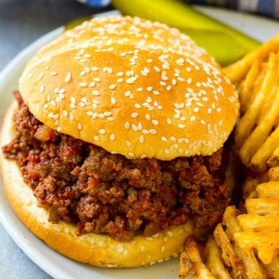 Slow cooker sloppy joe on a bun served with fries and pickles.
