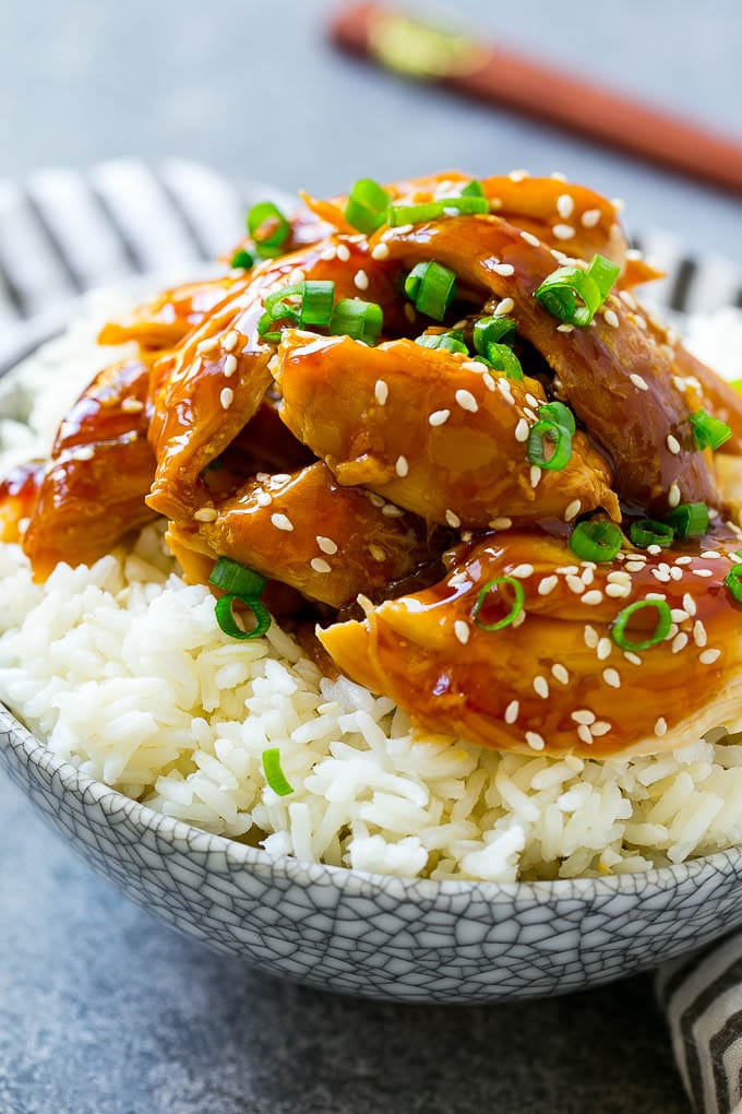 A bowl of rice topped with shredded crock pot teriyaki chicken.