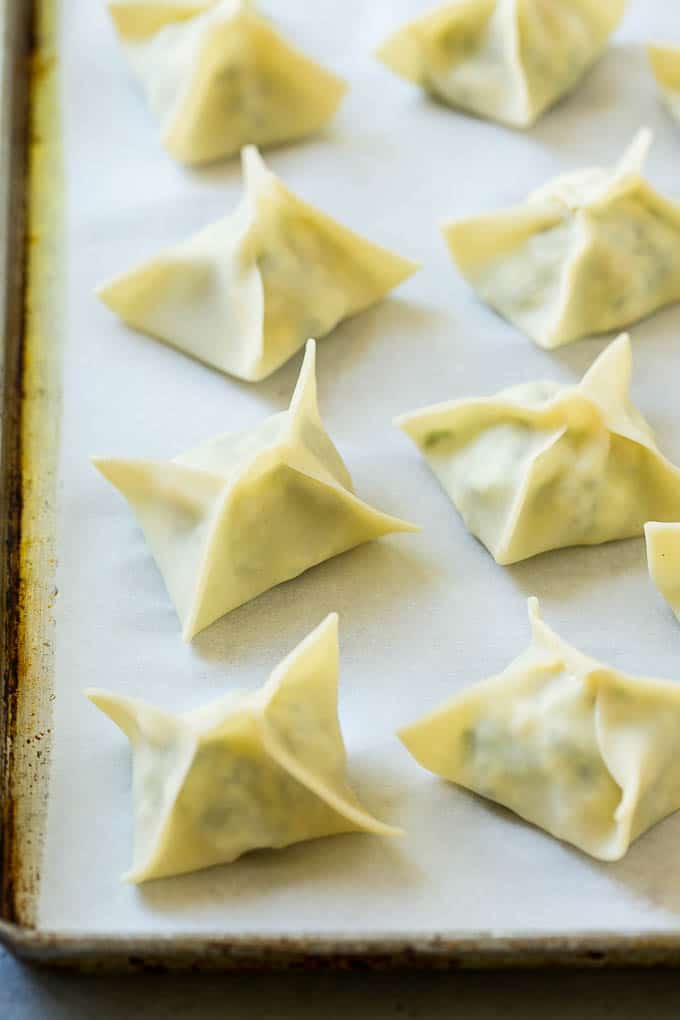 Folded wontons on a sheet pan.