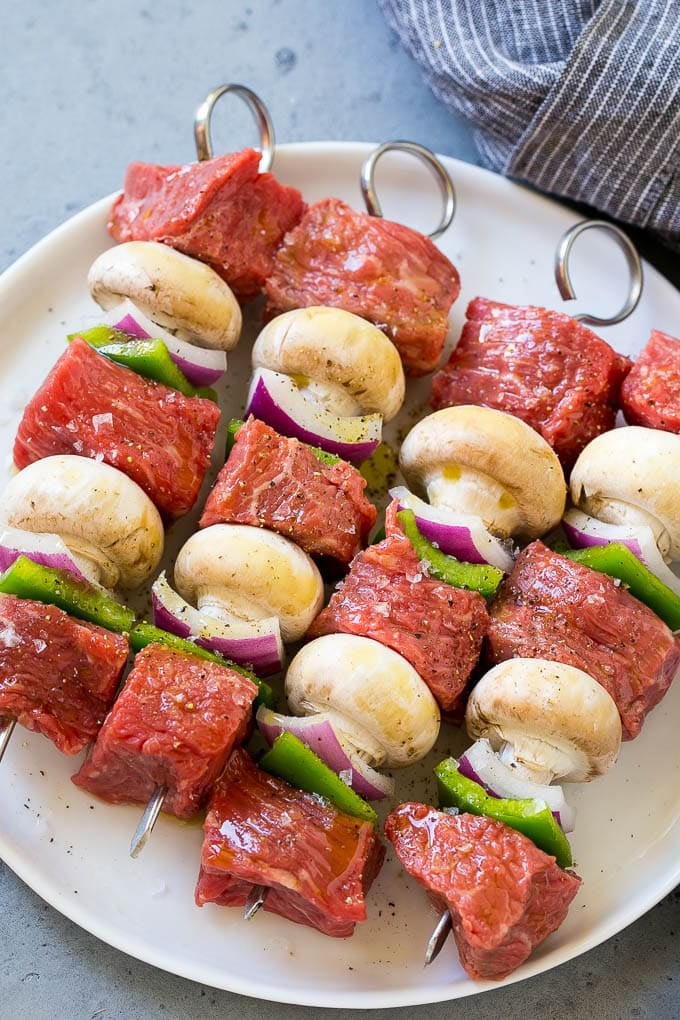 Skewers of beef, mushrooms, peppers and onions on a plate.