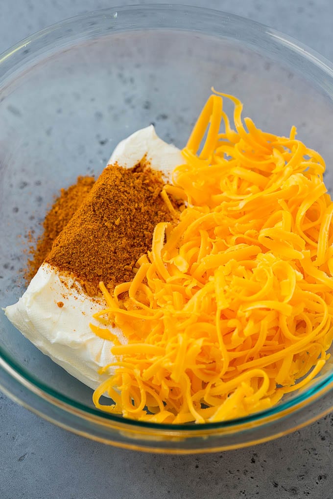 Cream cheese, cheddar cheese and taco seasoning in a bowl.