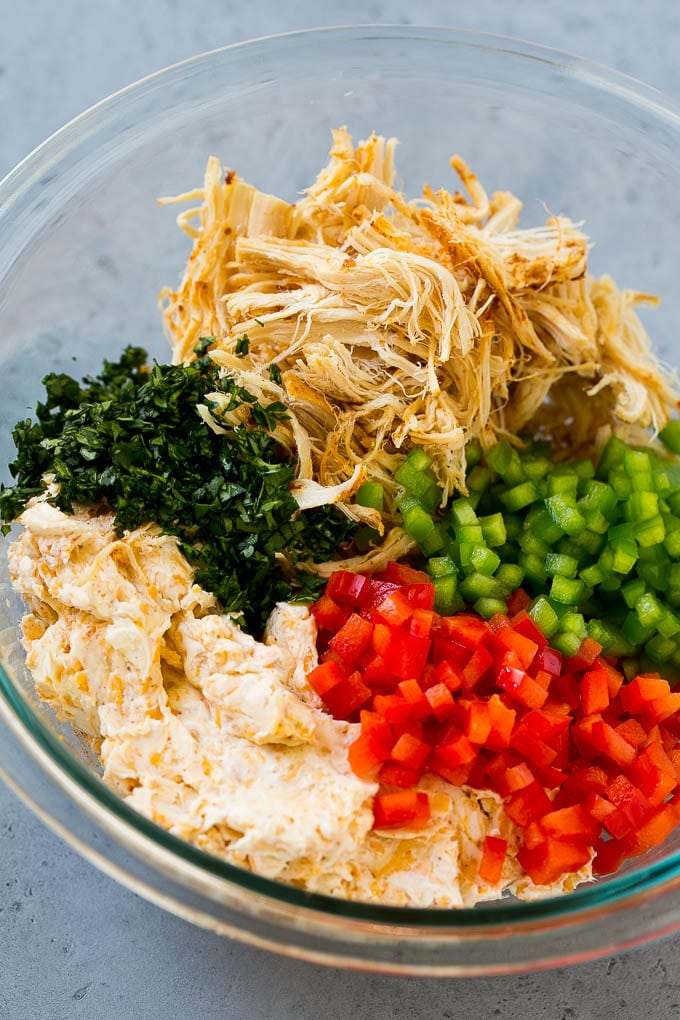 Cream cheese, chicken, bell peppers and cilantro in a bowl.