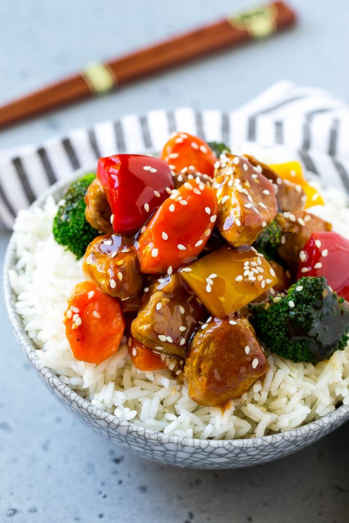 A bowl of rice with pork stir fry on top.