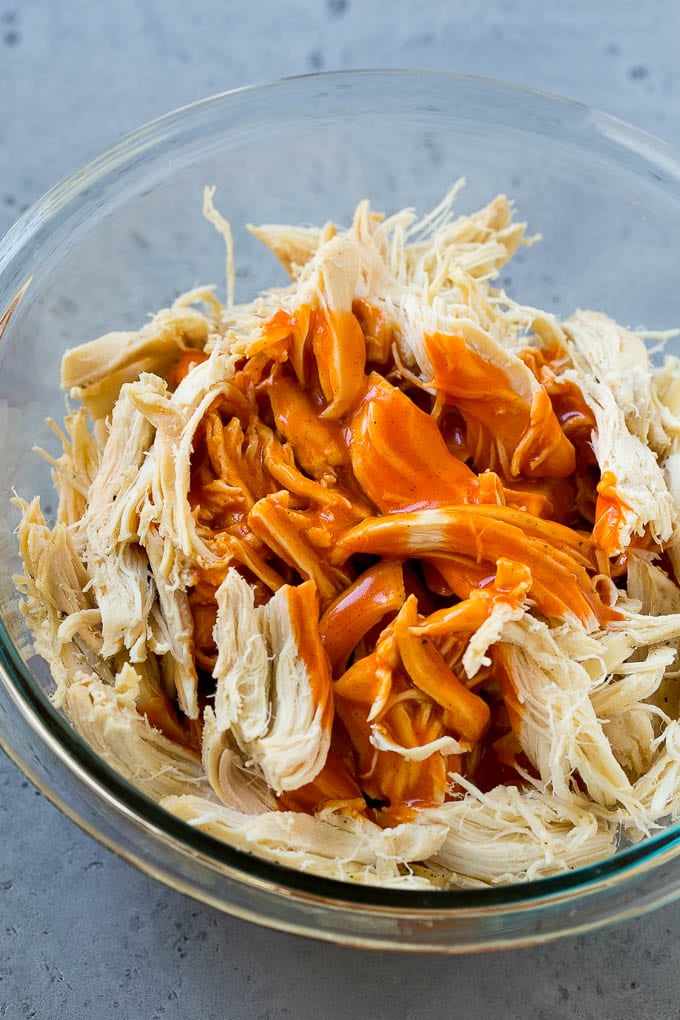 Shredded chicken in a bowl with buffalo sauce.