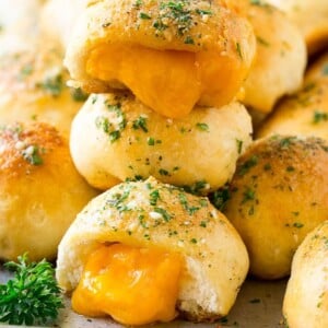 A stack of cheese bombs with melted cheddar cheese oozing out of them.