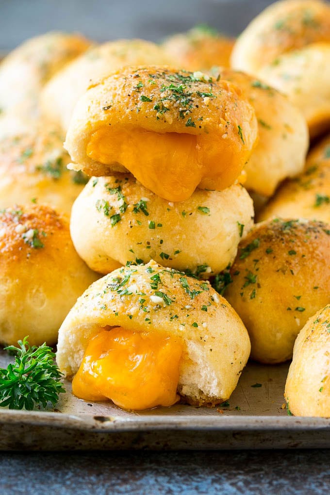 A stack of cheese bombs with melted cheddar cheese oozing out of them.
