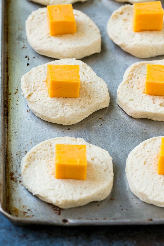Biscuit dough rounds topped with a cube of cheddar cheese.