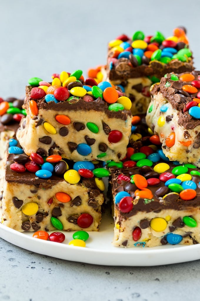 A plate of cookie dough bars studded with chocolate chips and M&M's.