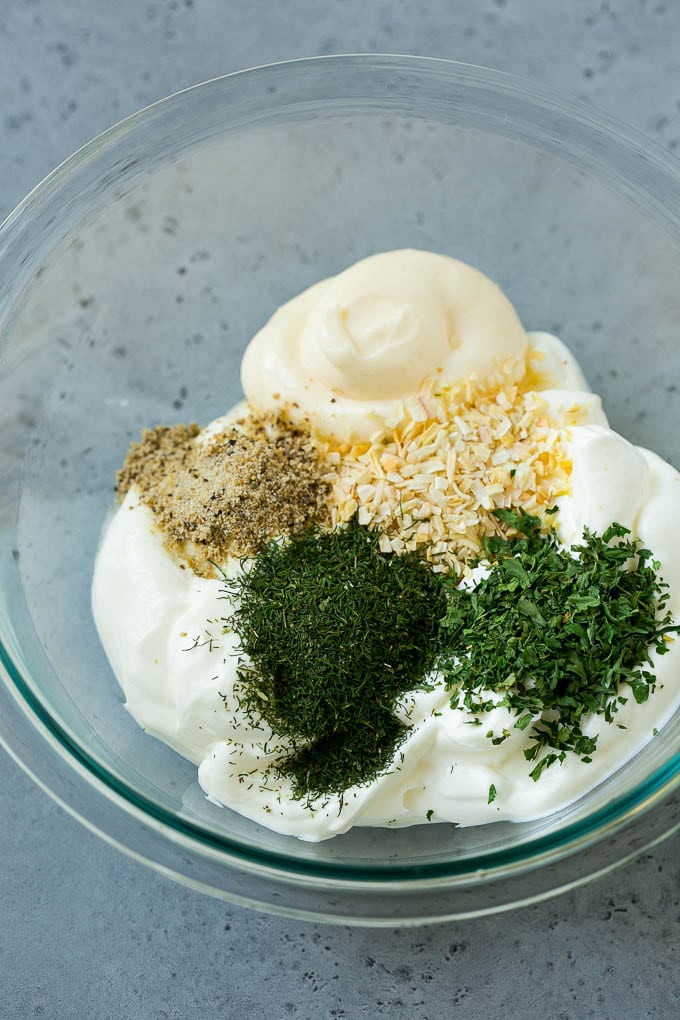 Sour cream and mayonnaise in a bowl with herbs, onion and spices.