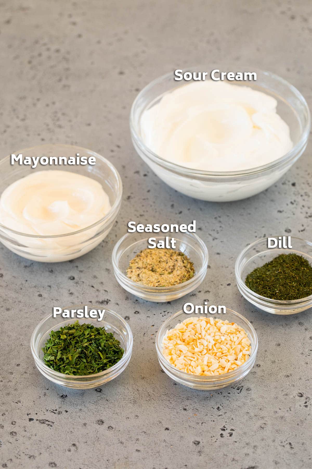 Bowls of ingredients including sour cream, mayonnaise and dried herbs and spices.