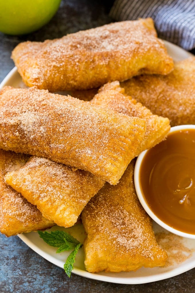 A plate of deep fried apple pies dusted with cinnamon sugar.