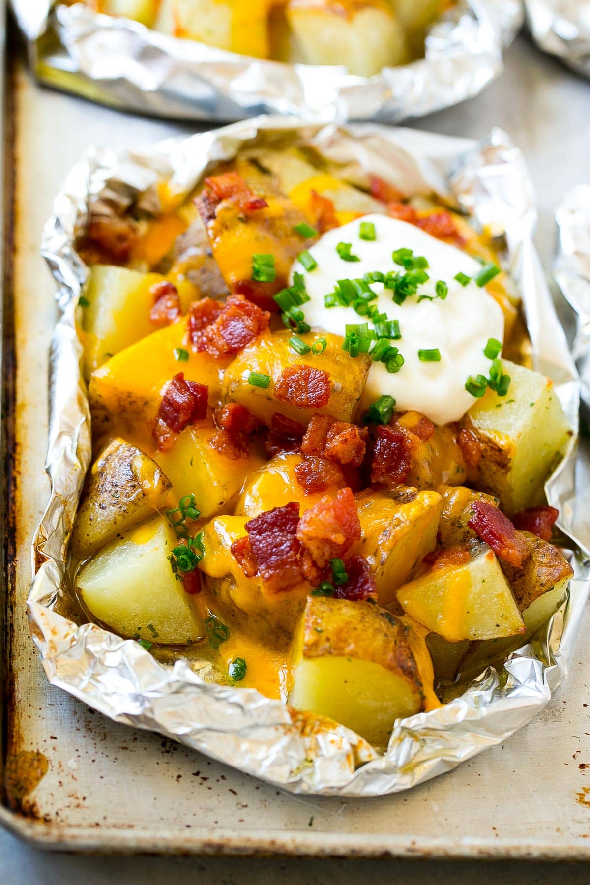 Grilled potatoes in foil with cheese, bacon and sour cream.