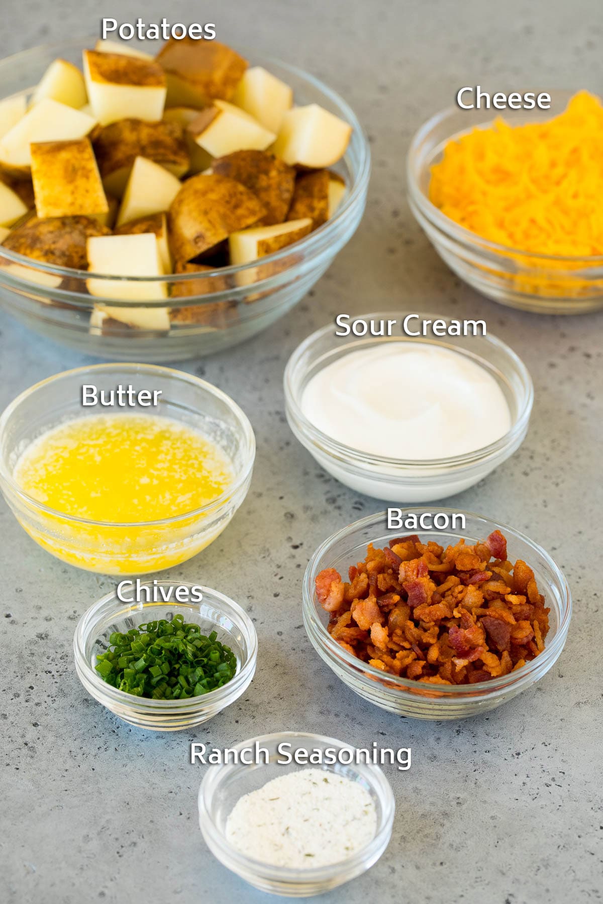 Bowls of ingredients including potatoes, butter, ranch seasoning, cheese and bacon.