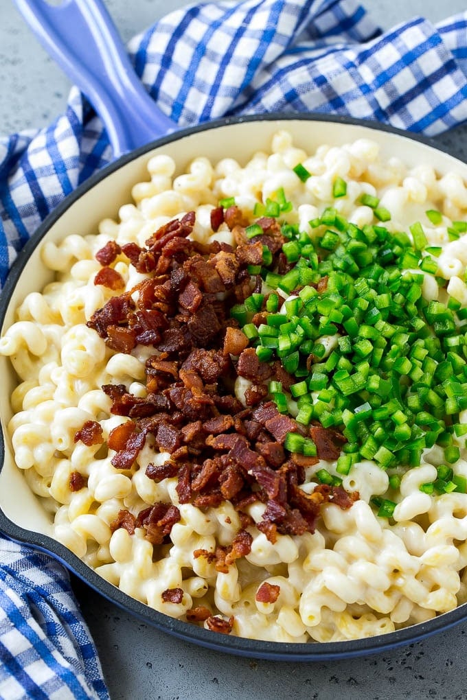 Macaroni and cheese in a skillet topped with bacon and diced jalapenos.