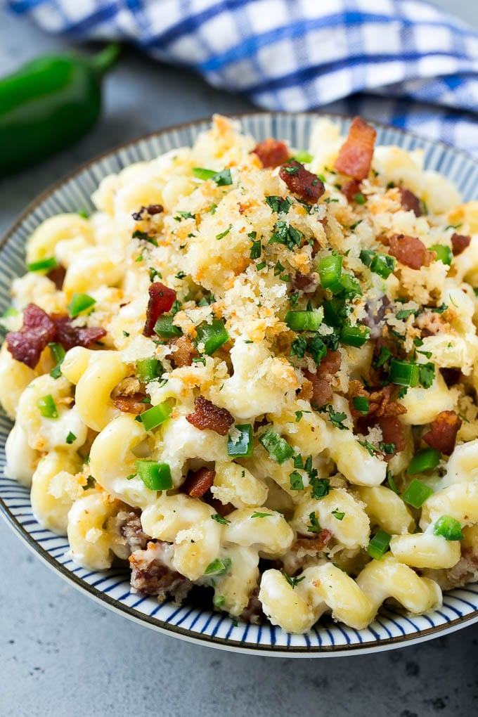 A bowl of jalapeno popper mac and cheese topped with crispy breadcrumbs, bacon and jalapeno peppers.