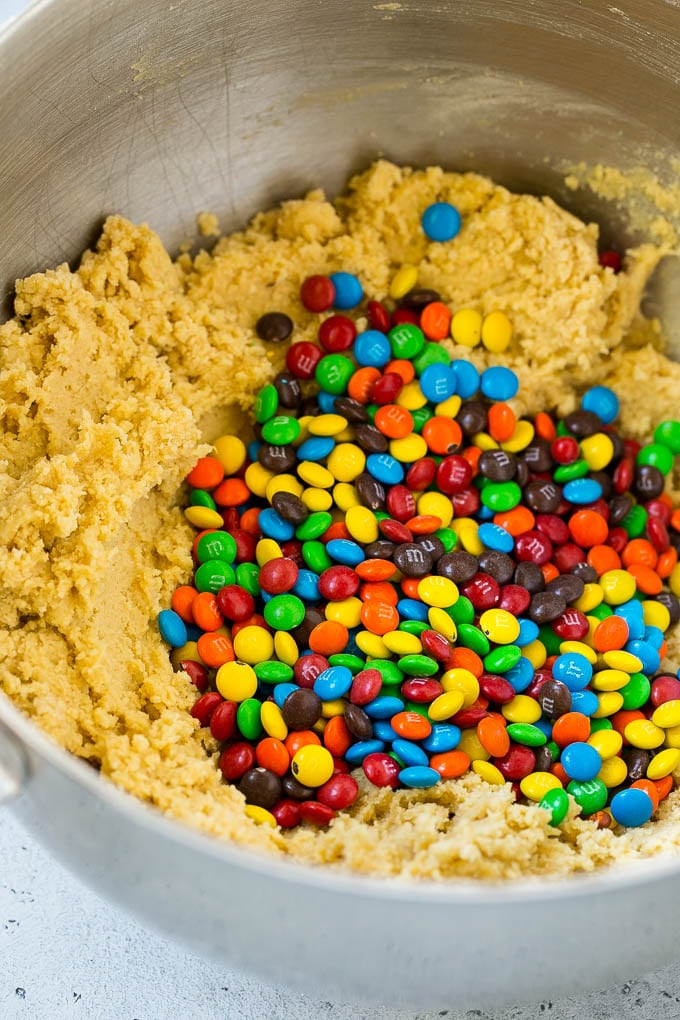 Cookie dough in a mixing bowl with miniature M&M's in it.