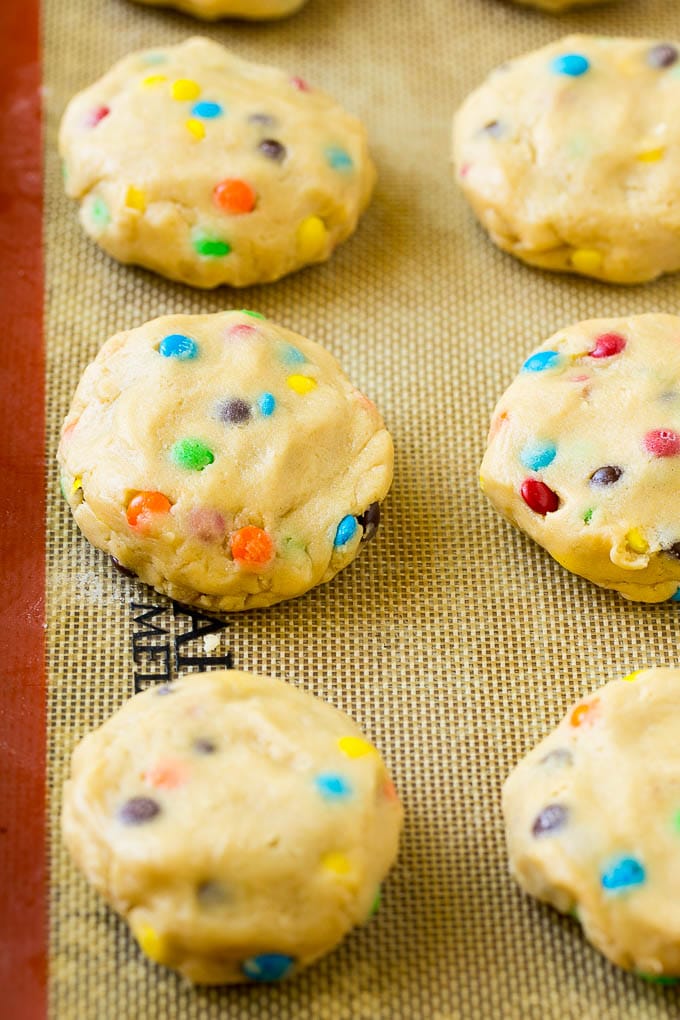 Cookie dough balls stuffed with Oreo cookies on a sheet pan.