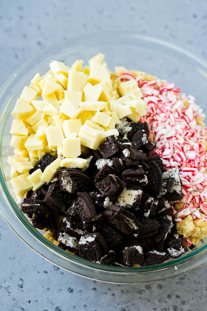 A bowl of dough with Oreo pieces, white chocolate chunks and crushed candy canes.