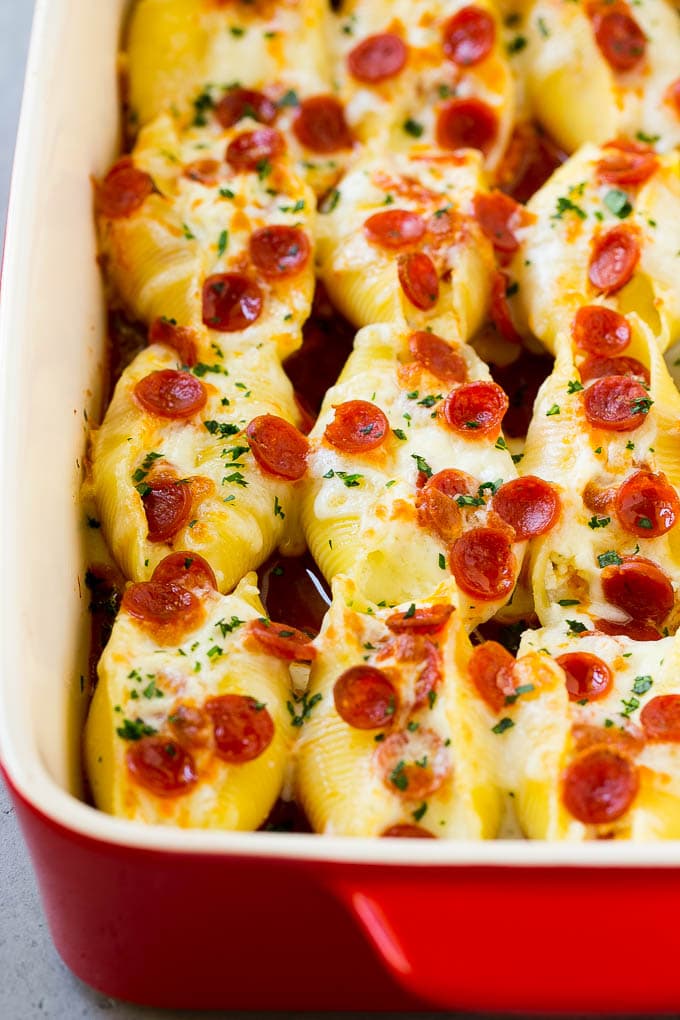 A baking dish full of pizza stuffed shells, topped with melted cheese and pepperoni.