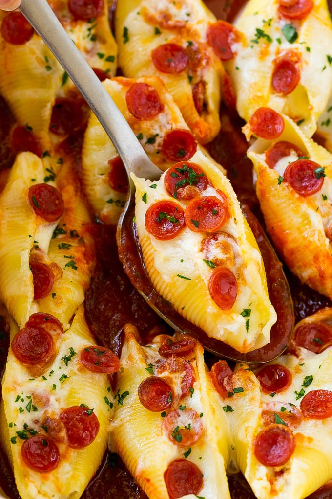 Pizza stuffed shells with a serving spoon.