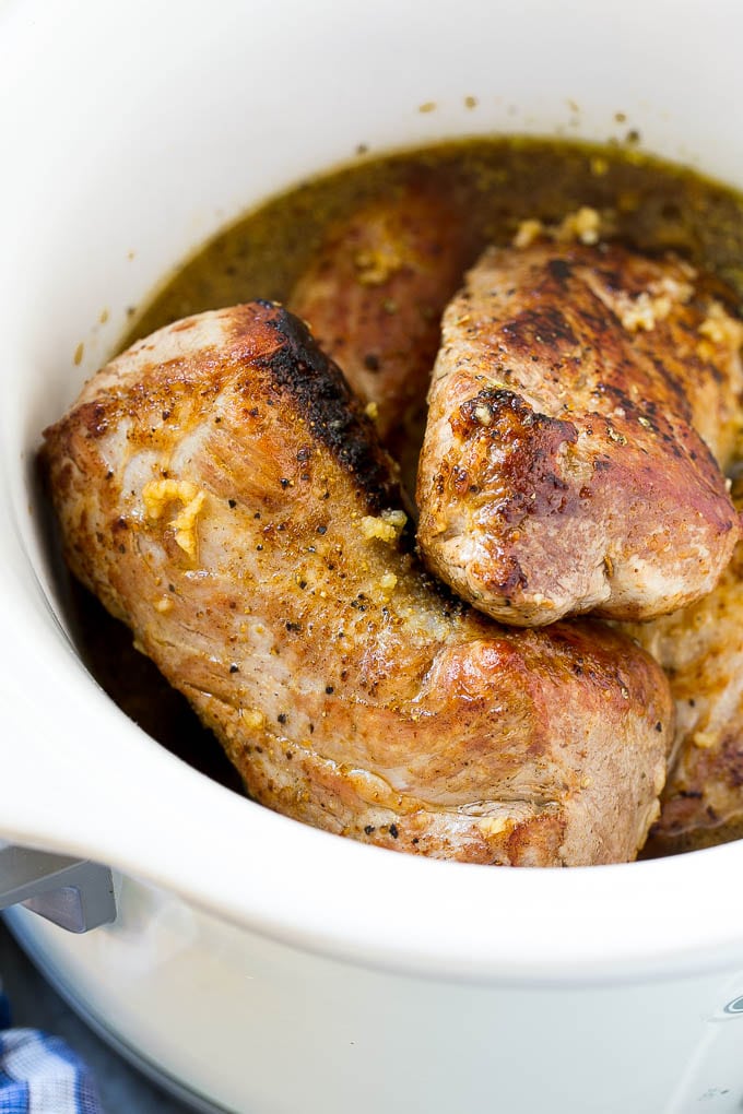 Seared pork tenderloin in a slow cooker with seasonings.