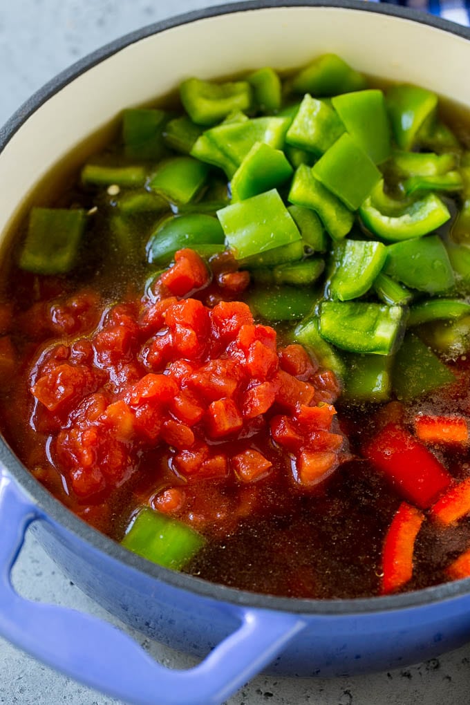 Ground beef, tomatoes, peppers and beef broth in a pot.