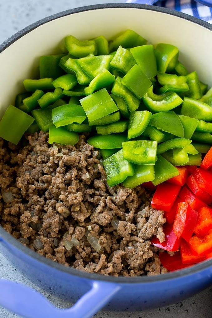 Cooked ground beef and bell peppers in a soup pot.