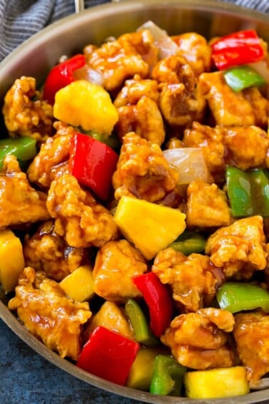 A frying pan of sweet and sour chicken with crispy chicken, pineapple, bell peppers and onions.