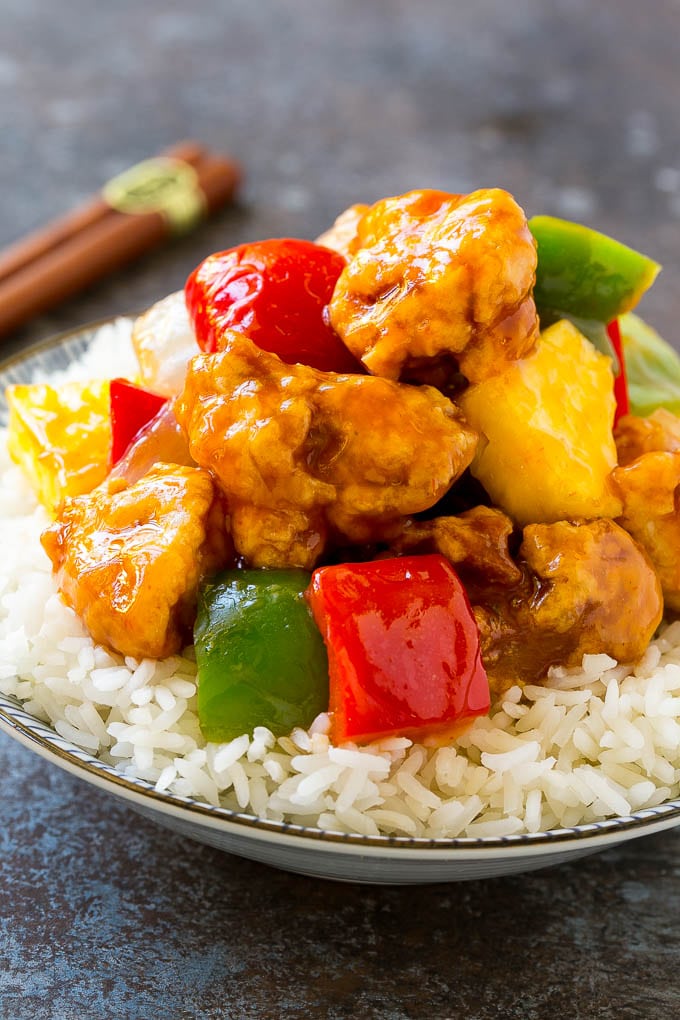 A bowl of sweet and sour chicken, served over steamed rice.