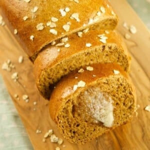 A loaf of brown bread on a wooden board.