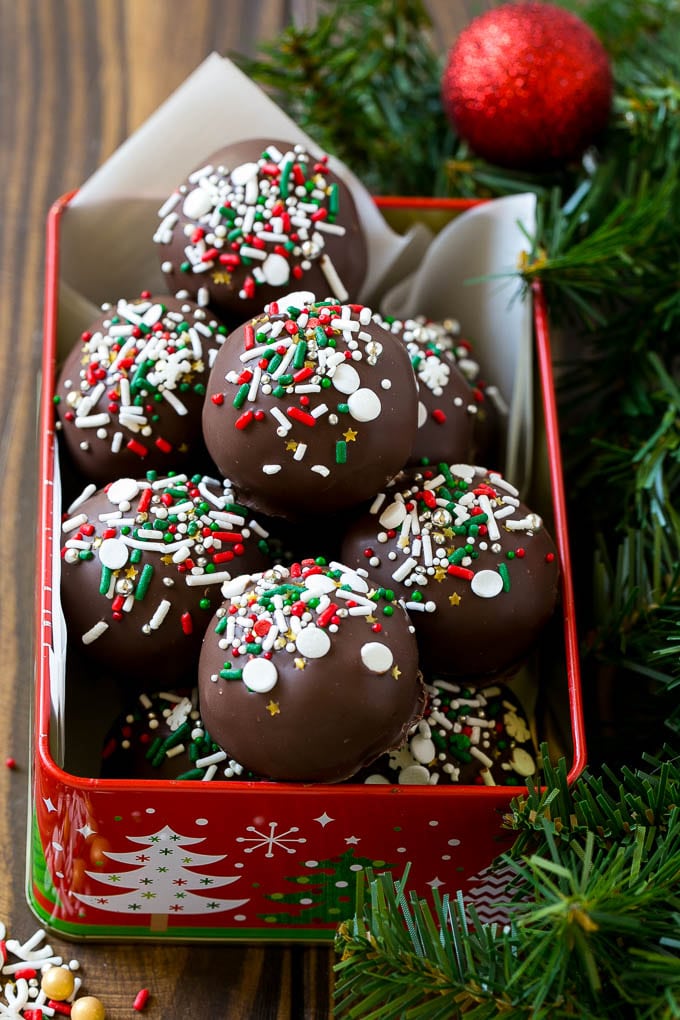 Cake truffles in a gift tin coated in dark chocolate and sprinkles.