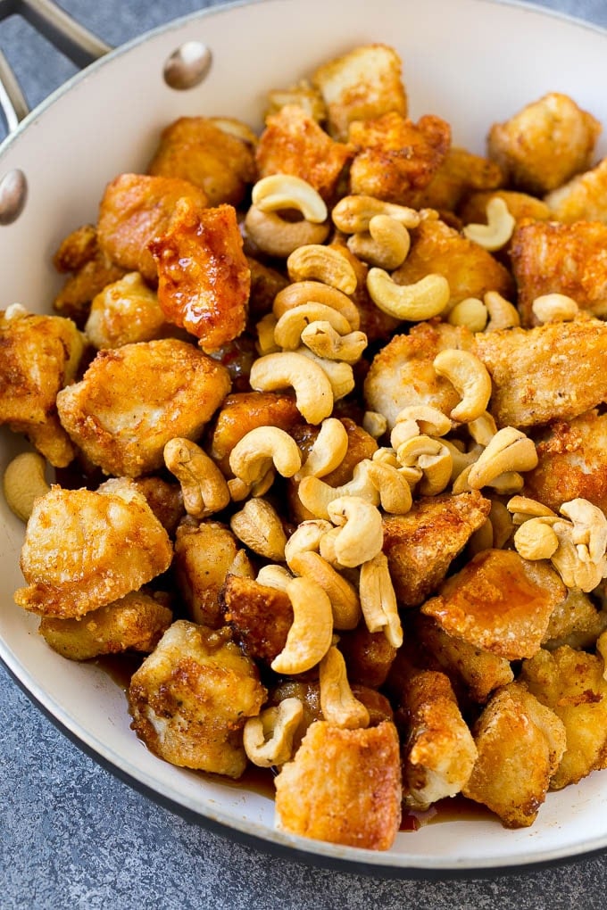 Crispy chicken pieces in a pan with sauce and roasted cashews.