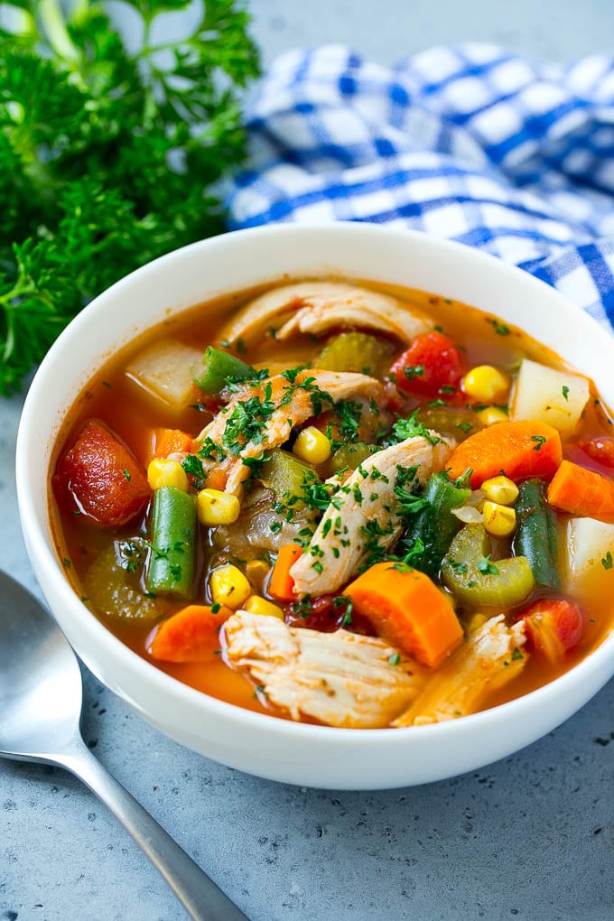 A bowl of chicken vegetable soup topped with parsley.