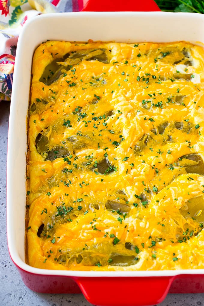 A dish of chile relleno casserole topped with cheddar cheese and chopped cilantro.