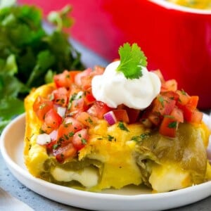 A slice of chile relleno casserole with pico de gallo and sour cream on top.