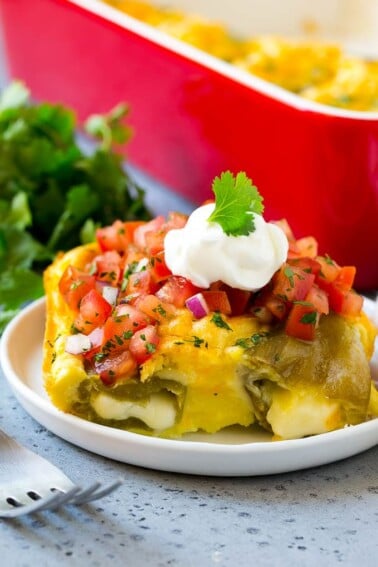 A slice of chile relleno casserole with pico de gallo and sour cream on top.