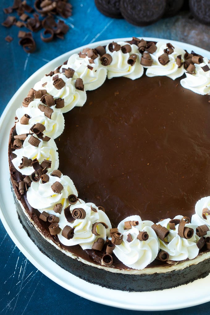 A no bake Oreo cheesecake topped with chocolate ganache, whipped cream and chocolate curls.