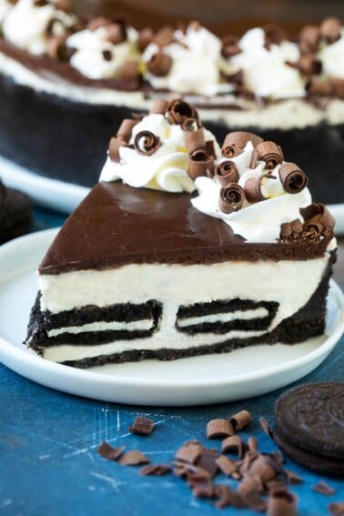 A slice of no bake Oreo cheesecake with a cookie crust, cheesecake and Oreo filling and chocolate topping.