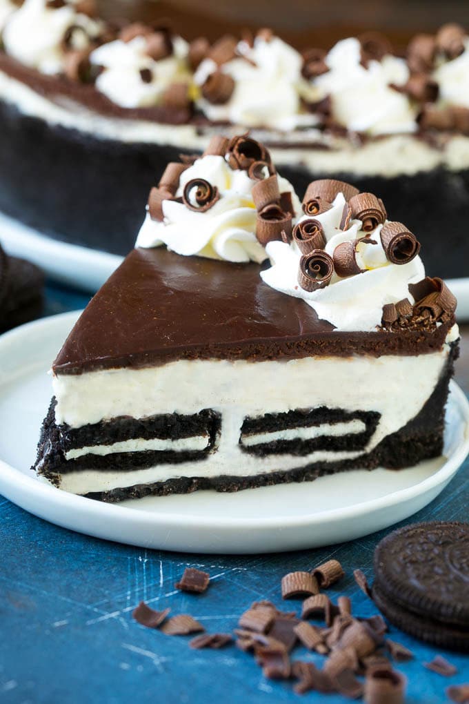 A slice of no bake Oreo cheesecake with a cookie crust, cheesecake and Oreo filling and chocolate topping.