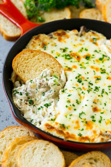 Philly cheesesteak dip with a baguette piece scooping some dip out.