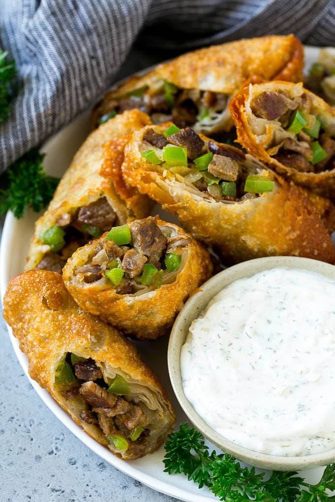 A plate of Philly cheesesteak egg rolls filled with diced steak, peppers, onions and cheese.