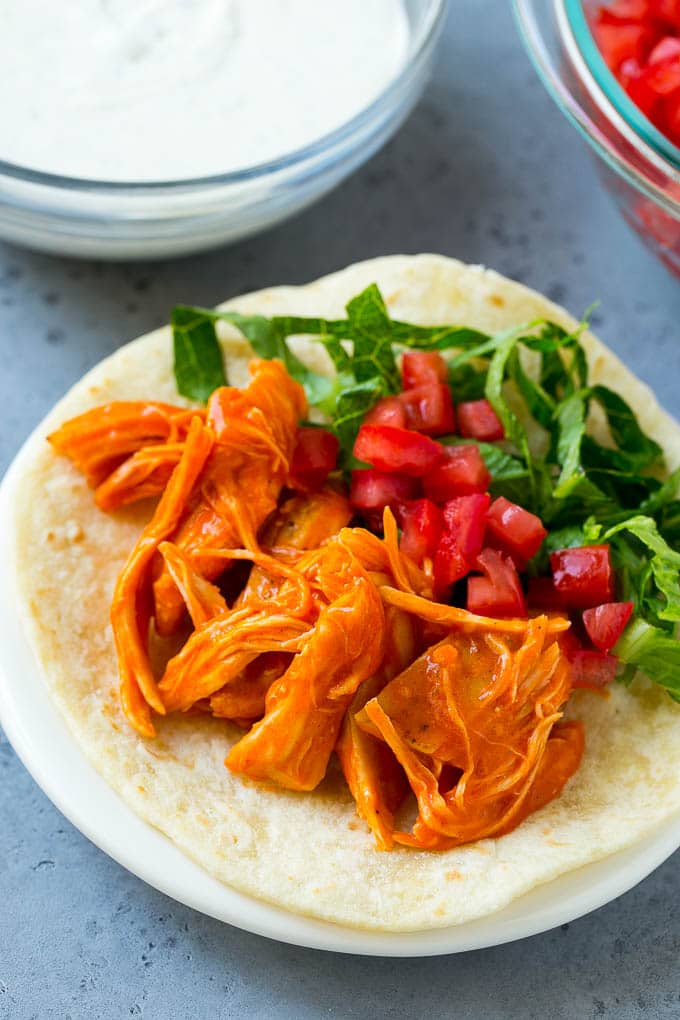 Buffalo chicken, tomatoes and shredded lettuce on a tortilla.