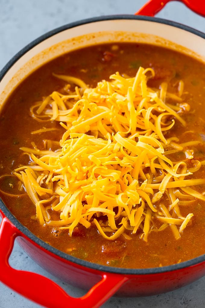 Chicken enchilada soup with cheddar cheese on top.