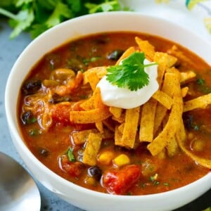 A bowl of chicken enchilada soup topped with tortilla strips, sour cream and cilantro.