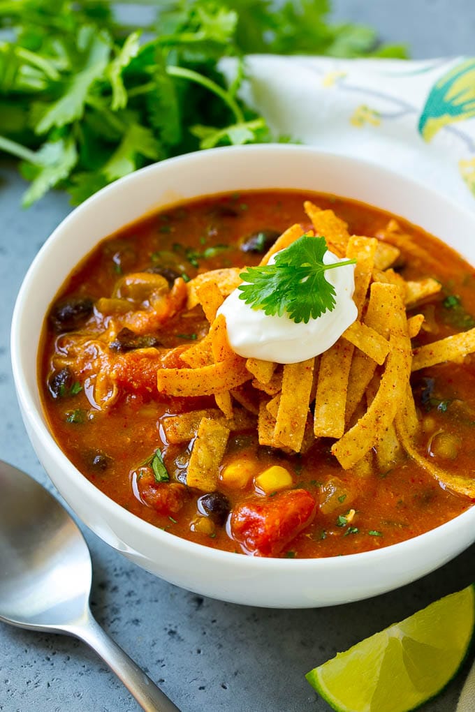 A bowl of chicken enchilada soup topped with tortilla strips, sour cream and cilantro.